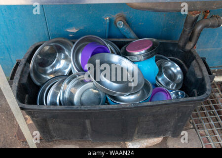 A close up view of metal dogs dishes piled up in a plastic black bucket Stock Photo