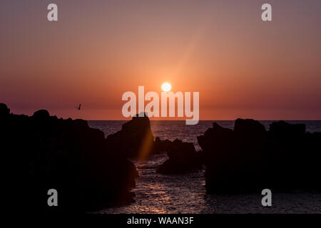 Sunset behind the rocky shore on the beach in Japan Stock Photo