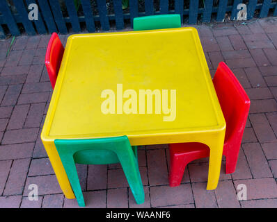 A close up top view of a colourful plastic kids table and chairs on the brick playground Stock Photo