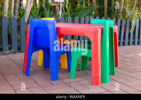 A close up side view of a colourful plastic kids table and chairs on the brick playground Stock Photo