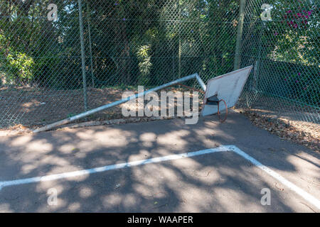 A close up view of a old  damaged basketball hoop that has fallen down on an abandoned tennis court Stock Photo