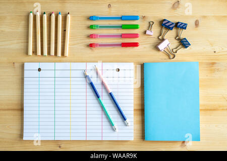 Sets of pens and crayons, clips, book in blue cover and lined notebook page Stock Photo