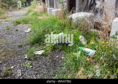 Empty food packagign and beer cans left on the floor littering the place. A dirty eyesore. Stock Photo