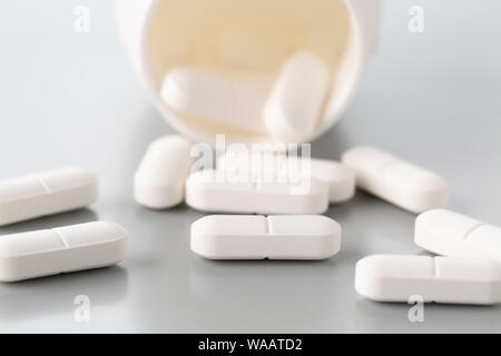 Scattered pills made of white plastic bottles on a light grey background Stock Photo