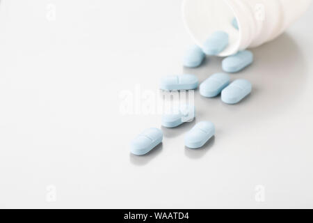 Scattered pills made of white plastic bottles on a light grey background Stock Photo