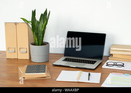 Workplace of office manager with laptop, potted plant, notebooks and books Stock Photo