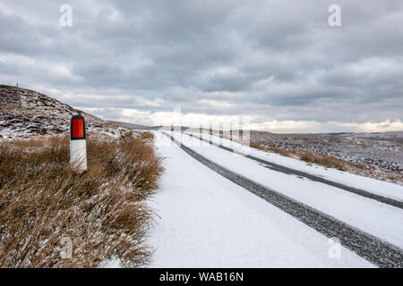 Clear tyre tracks on a snowy road in a rural setting with a stormy sky and room for copy Stock Photo