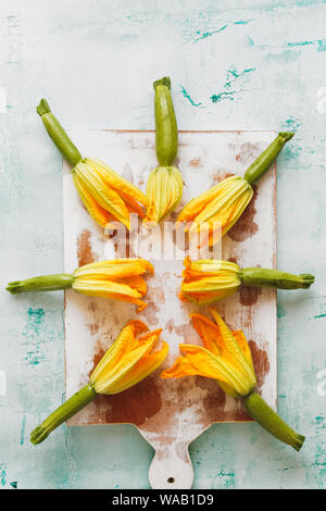 Courgettes with flowers on an old chopping board. Top view, blank space Stock Photo