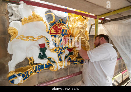 Colin Morris, from Nevin of Edinburgh Painters, applies gold leaf to one of the royal coats of arms during renovation work on the main facade of Canongate Kirk in Edinburgh. Stock Photo