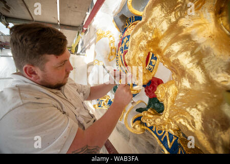Colin Morris, from Nevin of Edinburgh Painters, applies gold leaf to one of the royal coats of arms during renovation work on the main facade of Canongate Kirk in Edinburgh. Stock Photo