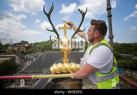 Colin Morris, from Nevin of Edinburgh Painters, applies gold leaf to the stags head on the roof apex during renovation work on the main facade of Canongate Kirk in Edinburgh. Stock Photo