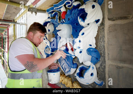 Colin Morris, from Nevin of Edinburgh Painters, paints one of the royal coats of arms during renovation work on the main facade of Canongate Kirk in Edinburgh. Stock Photo