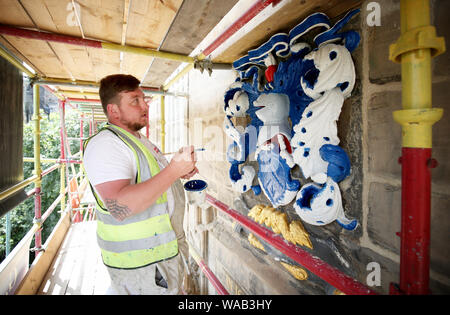 Colin Morris, from Nevin of Edinburgh Painters, paints one of the royal coats of arms during renovation work on the main facade of Canongate Kirk in Edinburgh. Stock Photo