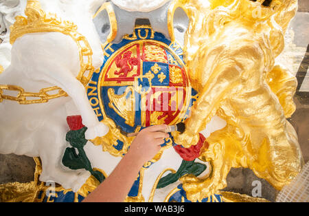 Colin Morris, from Nevin of Edinburgh Painters, applies gold leaf to one of the royal coats of arms during renovation work on the main facade of Canongate Kirk in Edinburgh. Stock Photo
