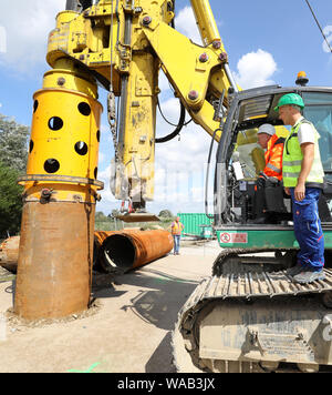 Tribsees, Germany. 19th Aug, 2019. Christian Pegel (SPD, l), Minister of Transport, sits in the driver's cab of a large drilling rig and operates the machine at the start of construction work on the sacked A20 Baltic Sea motorway, with construction worker Pascal Kreibe helping him. In the first construction phase, foundation piles are to be driven into the ground and around 80 metres of roadway in the direction of Rostock and Lübeck rebuilt, parts of the Trebeltal bridge are also to be repaired. Credit: Bernd Wüstneck/dpa-Zentralbild/dpa/17�Թ����� Live News Stock Photo