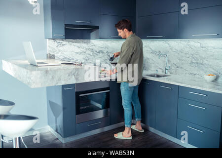 Man standing in the kitchen and making coffee in the morning Stock Photo