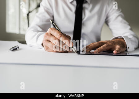 Front view of architect or designer working on a project drawing using pencil and ruler. Stock Photo