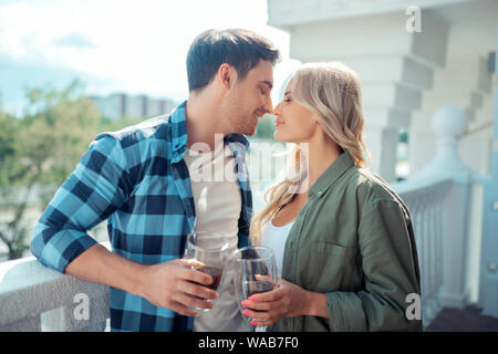 Couple kissing while drinking coffee standing on balcony Stock Photo