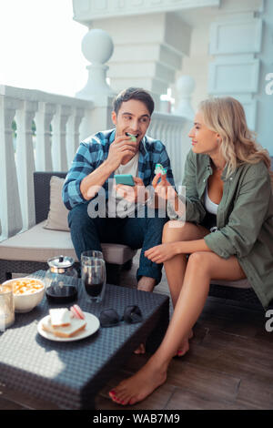 Good-looking couple sitting on balcony and having breakfast Stock Photo