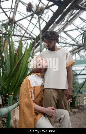 Man looking at dark-skinned men while standing in greenhouse Stock Photo