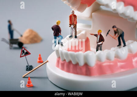 dental treatment concept - construction workers figurines on tooth model Stock Photo