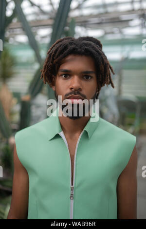Bearded male model with dreadlocks standing in greenhouse Stock Photo