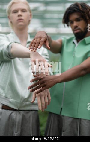 Men with different skin color posing and reaching out hands Stock Photo
