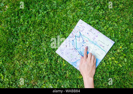 Woman hand holding a paper sheet with the travel map over green forest nature background. Ecology and greening concept, global Stock Photo