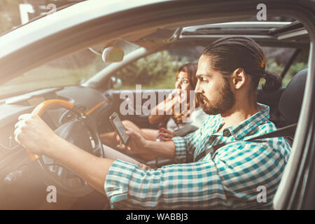 Couple in a car at sunset, man is driving fast and girl scared screaming and crying. Stock Photo