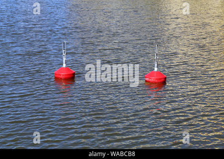 Two red buoys on top of the surface of Baltic Sea in Southern Helsinki, Finland, June 2019. Around the buoys you can see small waves. Stock Photo