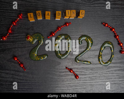 Loading for new 2020 year on wooden board, with text inscription, red garland, copy space Stock Photo