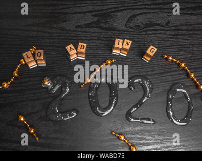 Loading for new 2020 year on wooden board, with text inscription, red garland, copy space Stock Photo