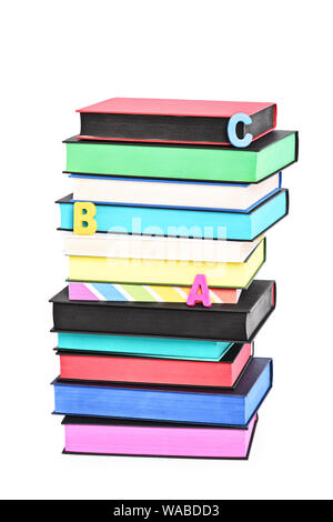 Stack of colorful books witch different sprayed edges and scattered letters spelling ABC, isolated on white background. Stock Photo