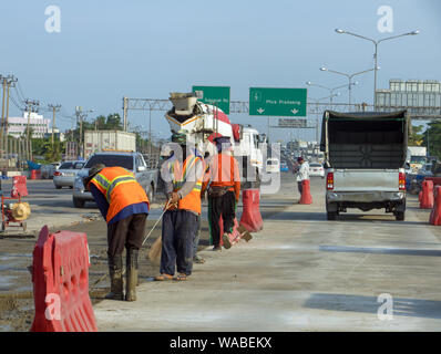 Workers repair roads during traffic. Reconstruction of highway surface in Bangkok, Thailand. Stock Photo