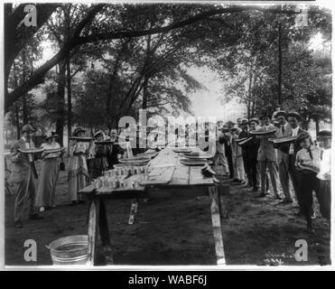 Commercial Club entertaining with watermelons and lemonade Abstract: Group holding large pieces of watermelons posed, standing around tables, Fairfield, Alabama. Stock Photo