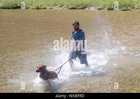 happy young man with his dog having fun swimming at river. Love animals love my pet Stock Photo