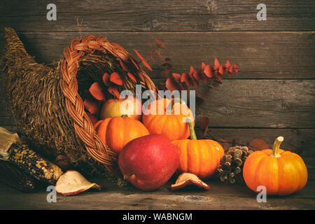 Thanksgiving cornucopia filled with pumpkins and apples against a rustic wooden background Stock Photo