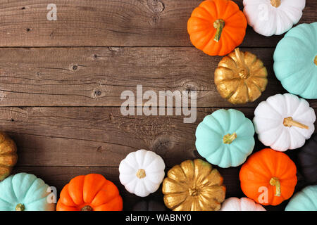 Autumn corner border of various colorful pumpkins on a rustic wood background. Top view with copy space. Stock Photo