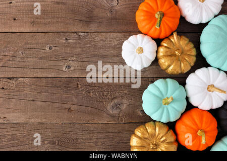 Autumn side border of various colorful pumpkins on a rustic wood background. Top view with copy space. Stock Photo