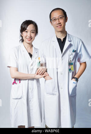 (190819) -- BEIJING, Aug. 19, 2019 (Xinhua) -- Jiang Nan (R), attending physician of rheumatology and immunology department, and his wife Liu He, resident physician of endocrinology department, pose for a photo at their work place of the Peking Union Medical College Hospital in Beijing, capital of China, Aug. 13, 2019. China has about 3.6 million qualified physicians and 4.1 million registered nurses. They have formed a strong force to support the most significant medical service system in the world of safeguarding the health of 1.4 billion people in the country.    China designated Aug. 19 as Stock Photo