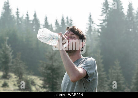 Boy drinking fresh water after long hike in forest Stock Photo