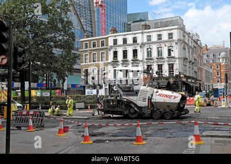 Road repair workers resurfacing street with tarmac at London Wall and Moorgate intersection on a Sunday in the City of London UK  KATHY DEWITT Stock Photo