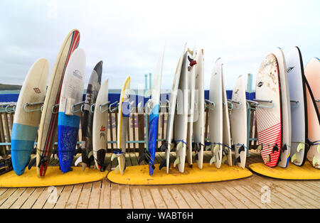 Newquay, Cornwall, UK. 16th Aug, 2019. Surfboards for Hire outside the Surf Hire shop on Newquay's famous Fistral Beach.UK's centre of Surfing is around the varied coastline and beaches of Cornwall in the very south west of the mainland. Surfers head there every summer and there are numerous, surf school, surf shops dotted around the popular Cornish towns. Credit: Keith Mayhew/SOPA Images/ZUMA Wire/Alamy Live News Stock Photo