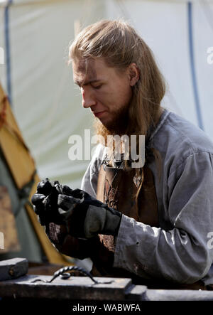 Hameenlinna Finland 08/17/2019 Medieval festival with craftsman, knights and entertainers.  A blacksmith cleaning and polishing his handwork Stock Photo