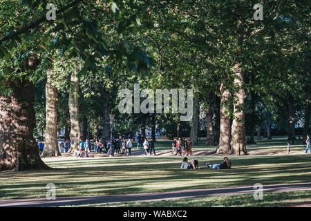 London, UK - July 15, 2019: People relaxing in a park on a hot summer day in London, UK. London experienced a number of heatwaves in 2019. Stock Photo