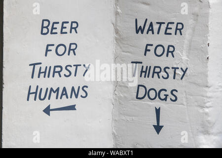 Beer for thirsty humans, water for thirsty dogs. Hand painted sign on a pub wall in Cirencester, Cotswolds, Gloucestershire, England