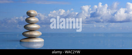 Zen stones stack from large to small in water with blue sky and