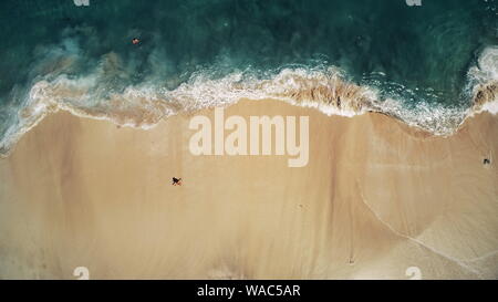 Aerial Top Drone View on Ocean Waves and White Sand Beach. Crystal Water Landscape in Tropical Bali Island, Indonesia. People Walk, Swim and Relax. Cinematic Filter Toning Stock Photo