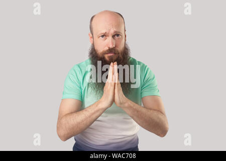 Please help me, forgive me or give me one chance more. Portrait of pleased middle aged bald bearded man standing with palm hands, looking and begging. Stock Photo