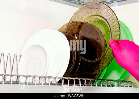 Dish dryer in the closet. White background. Plates of different colors. Cleaning, cleanliness Stock Photo
